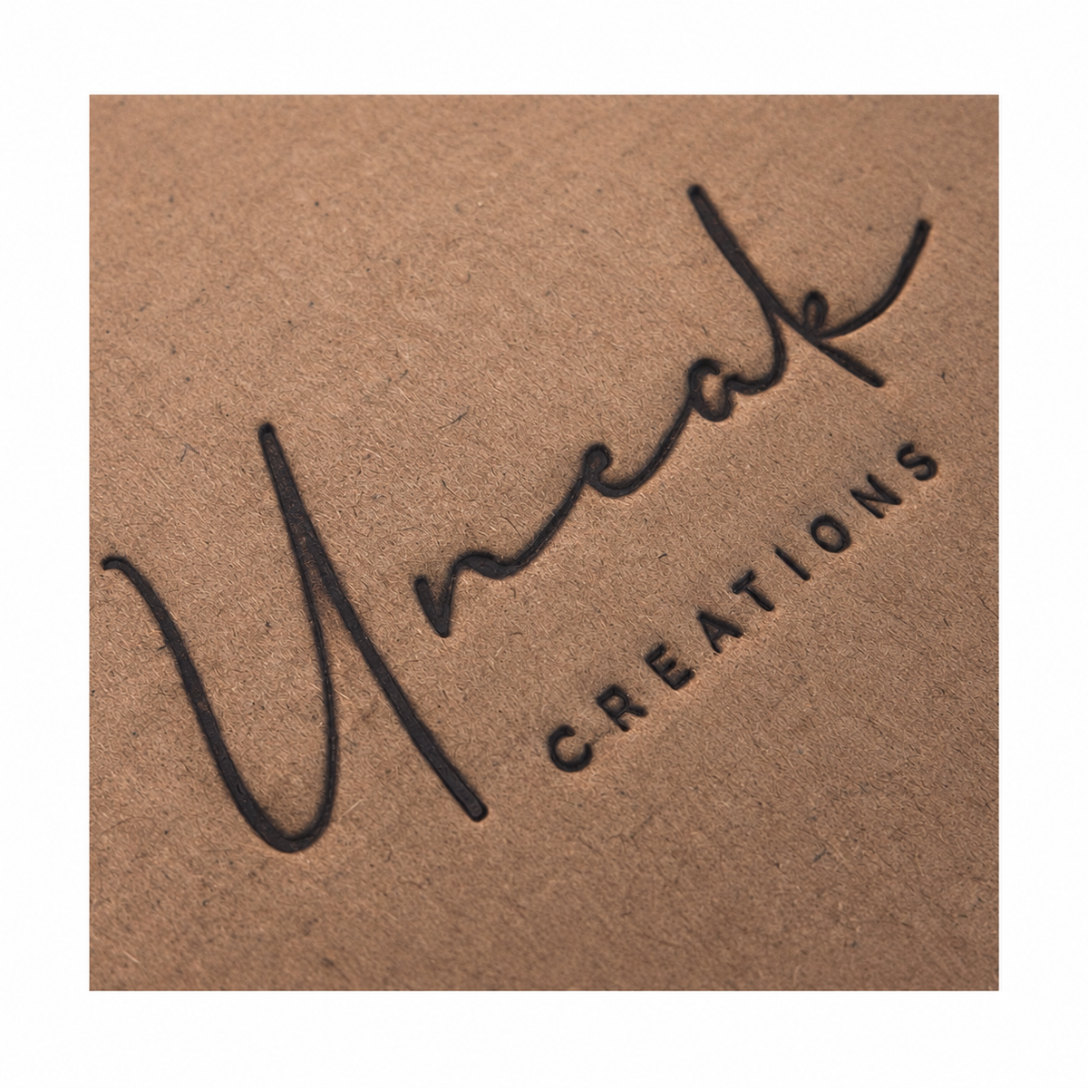 Uneak Creations branding on cardboard from our Instagram archive, cropped and edited with white margins